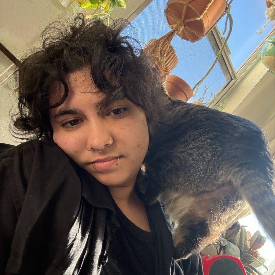 Atlas Blue Martinez with their cat on their shoulder